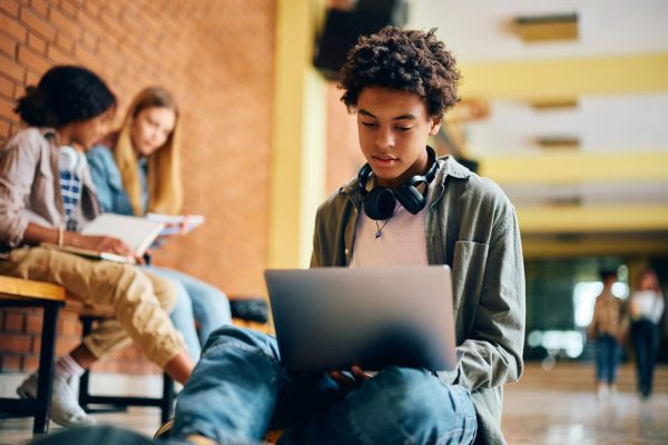 black-high-school-student-surfing-the-net-on-laptop-in-a-hallway-.jpg